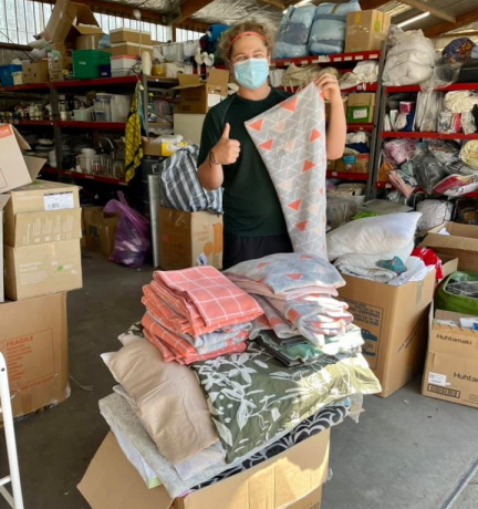 One of the workers for Re-Source HB sorts a pile of pet beds and blankets upcycled by the Sewing Room Crew.