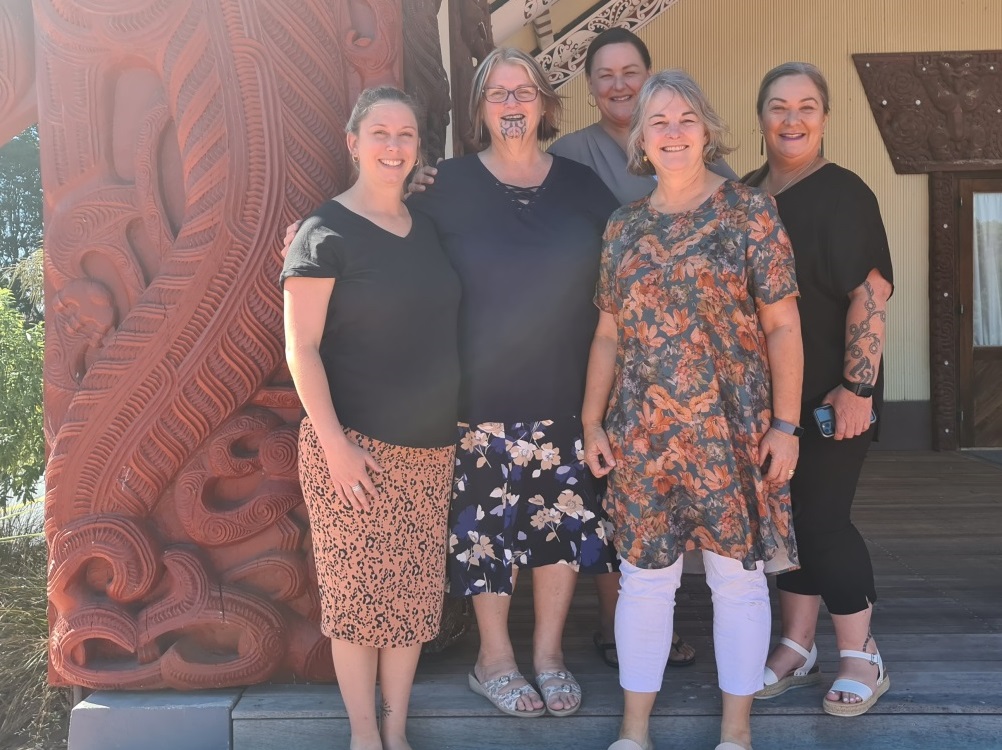 Five women standing in front Marae. (L-R) District Manager Canterbury Toni Stewart, Pou Tikanga Louise Tankersley, Prison Director Christchurch Women’s Prison Deb Alleyne, Regional Manager Māori Partnerships Team Nicola Schwass, Senior Advisor Māori Partnerships Rautaki Māori (Project Lead, Te Mana Wāhine Pathway) Justine Pardoe.