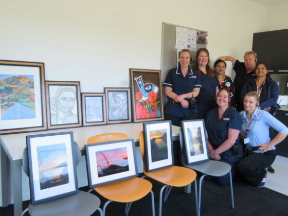 Health Centre staff with the artworks. Frames for the art were made by men in the prison using wooden floorboards from the old prison gym.