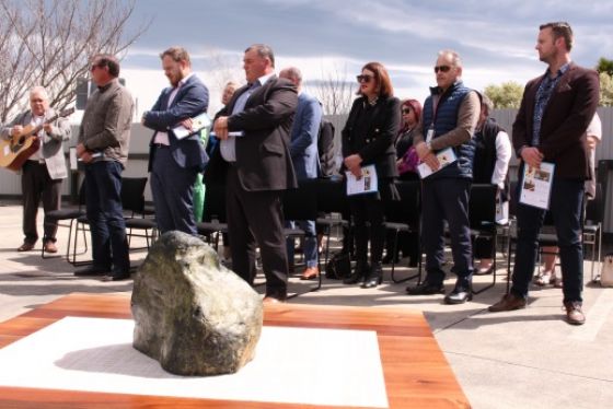 A mauri stone donated by a community member in the foreground with people standing in the background.