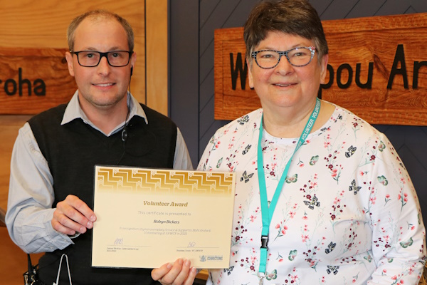 Volunteer lead of the Sewing, Quilts and Crafts programmme Robyn Bickers (right) receives a certificate of acknowledgment from ARWCF Regional Volunteer Co-ordinator Stephen Jones. 